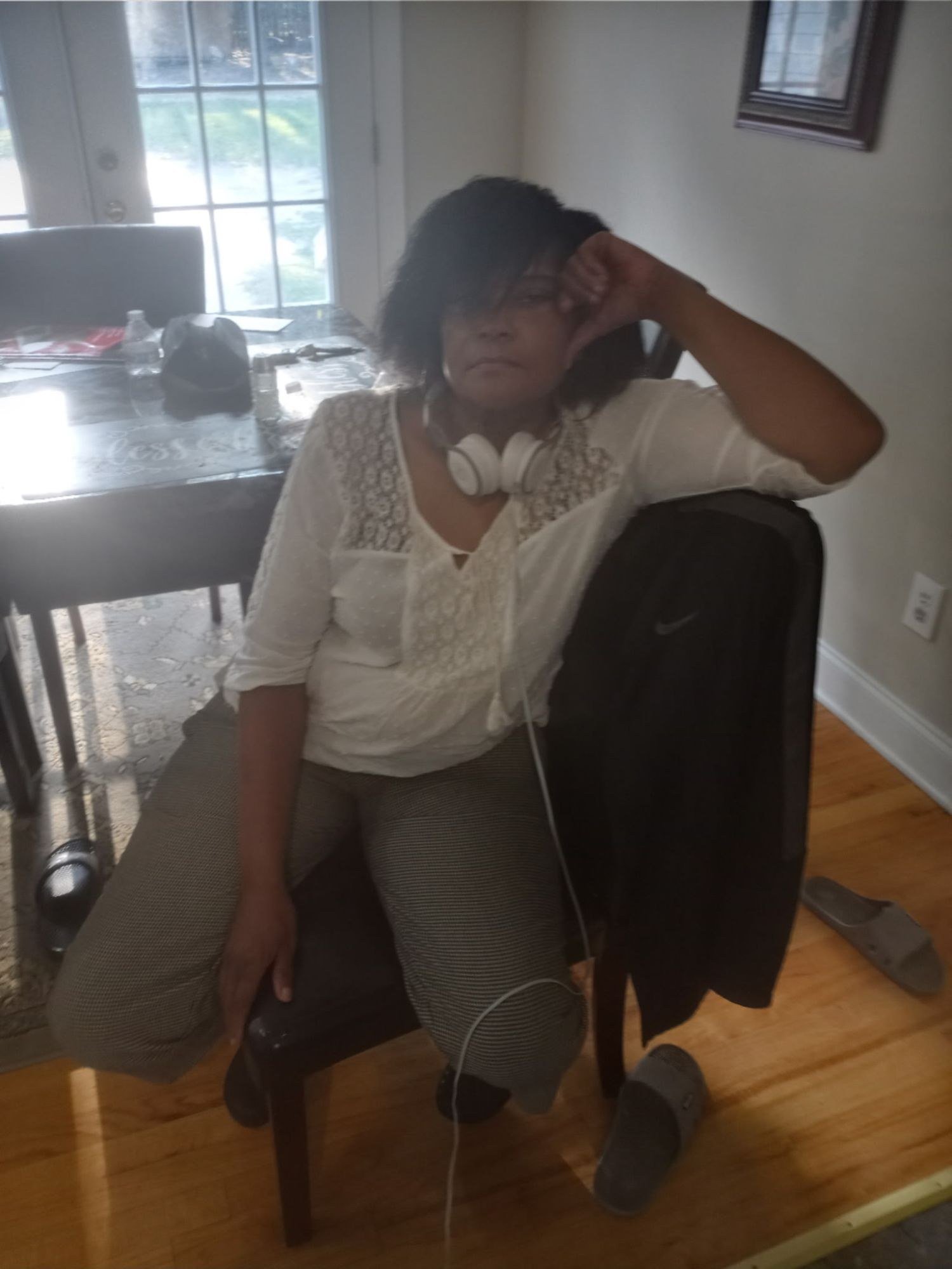 Portrait of Edna Gore seated at home, wearing a white lace blouse with headphones around her neck